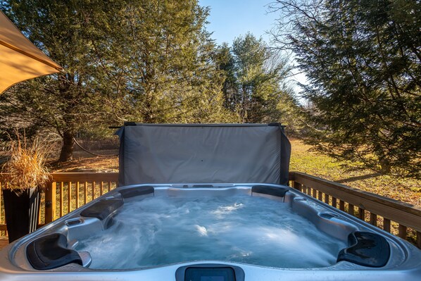 Un jacuzzi con cubierta de madera y dosel, rodeado de árboles.