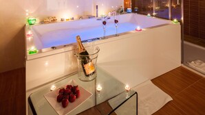 Ein modernes Badezimmer mit einer großen Badewanne, einer Champagnerflasche und Erdbeeren auf einem Tablett.
