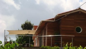 A wooden cabin with a circular window, a covered patio area, and a clear sky. - Bed and Breakfast in the hinterland of Monaco (Peille)