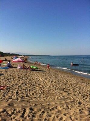 Une plage de sable avec des parasols et des gens.