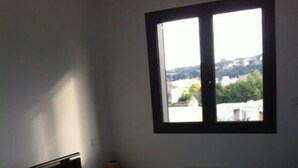 Een slaapkamer met een bed, een raam en een radiator.