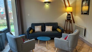 A living room with a dark blue sofa, two armchairs, a small blue table, and a floor lamp.