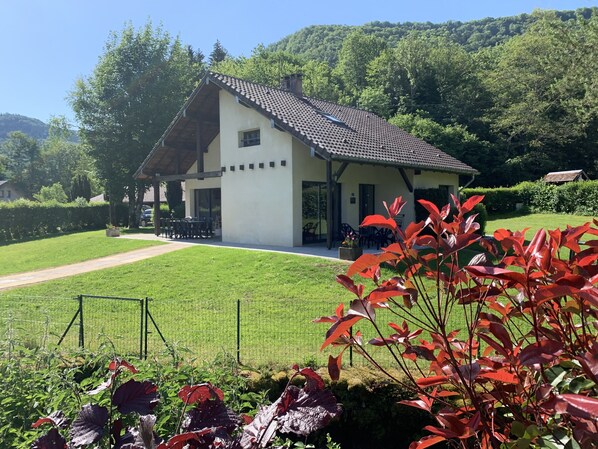 A two-story house with a sloped roof, a covered porch, and a well-maintained lawn. - Cottage 5 people on the quiet riverside le Lizon
in Franche Comté (Nans-Sous-Sainte-Anne)