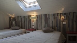 A room with two beds, a skylight, and a wall with vertical wooden slats.