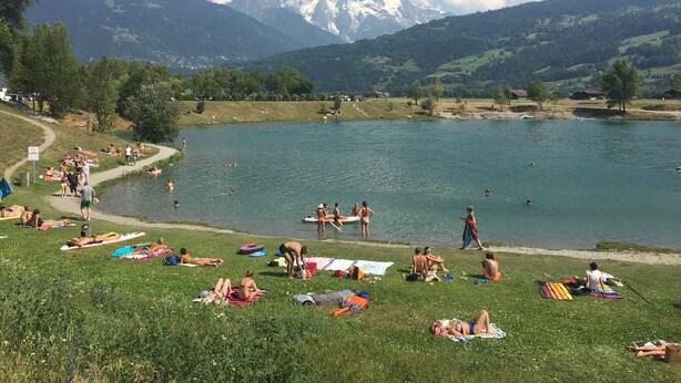 A lakeside view with people sunbathing and swimming, surrounded by mountains and greenery. - Superb Central Chamonix Apartment, Great Views, next to the beginners slopes (Chamonix-Mont-Blanc)