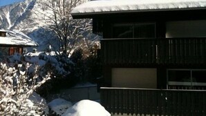 A two-story building with a snow-covered roof and a garage door. - Superb Central Chamonix Apartment, Great Views, next to the beginners slopes (Chamonix-Mont-Blanc)