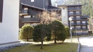 A building with multiple balconies and a paved pathway. - Superb Central Chamonix Apartment, Great Views, next to the beginners slopes (Chamonix-Mont-Blanc)