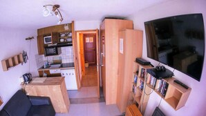 A compact living space with a kitchenette, a flat-screen TV, a sofa, and a wooden cabinet. - Superb Central Chamonix Apartment, Great Views, next to the beginners slopes (Chamonix-Mont-Blanc)