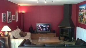 Una sala de estar con un sofá, televisión, chimenea y paredes rojas.