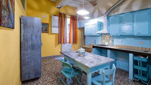 A compact kitchen with teal cabinets, a granite countertop, and a dining area with a table and chairs.