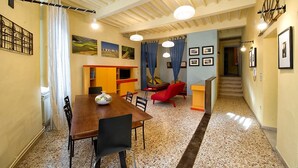 A dining area with a wooden table and chairs, a kitchen area with a TV, and a staircase leading to another level.