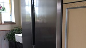 Un réfrigérateur en acier inoxydable dans une cuisine, avec une fenêtre au-dessus.