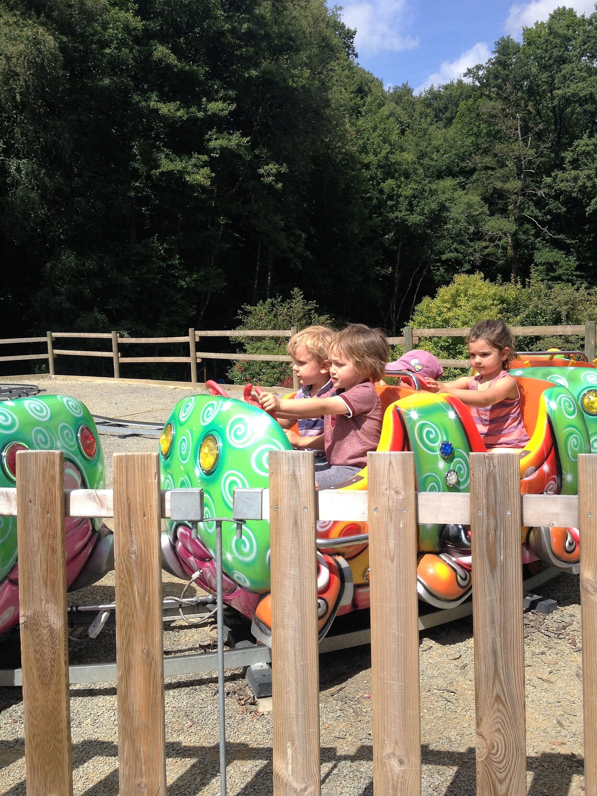 A wooden fence with a roller coaster track behind it.