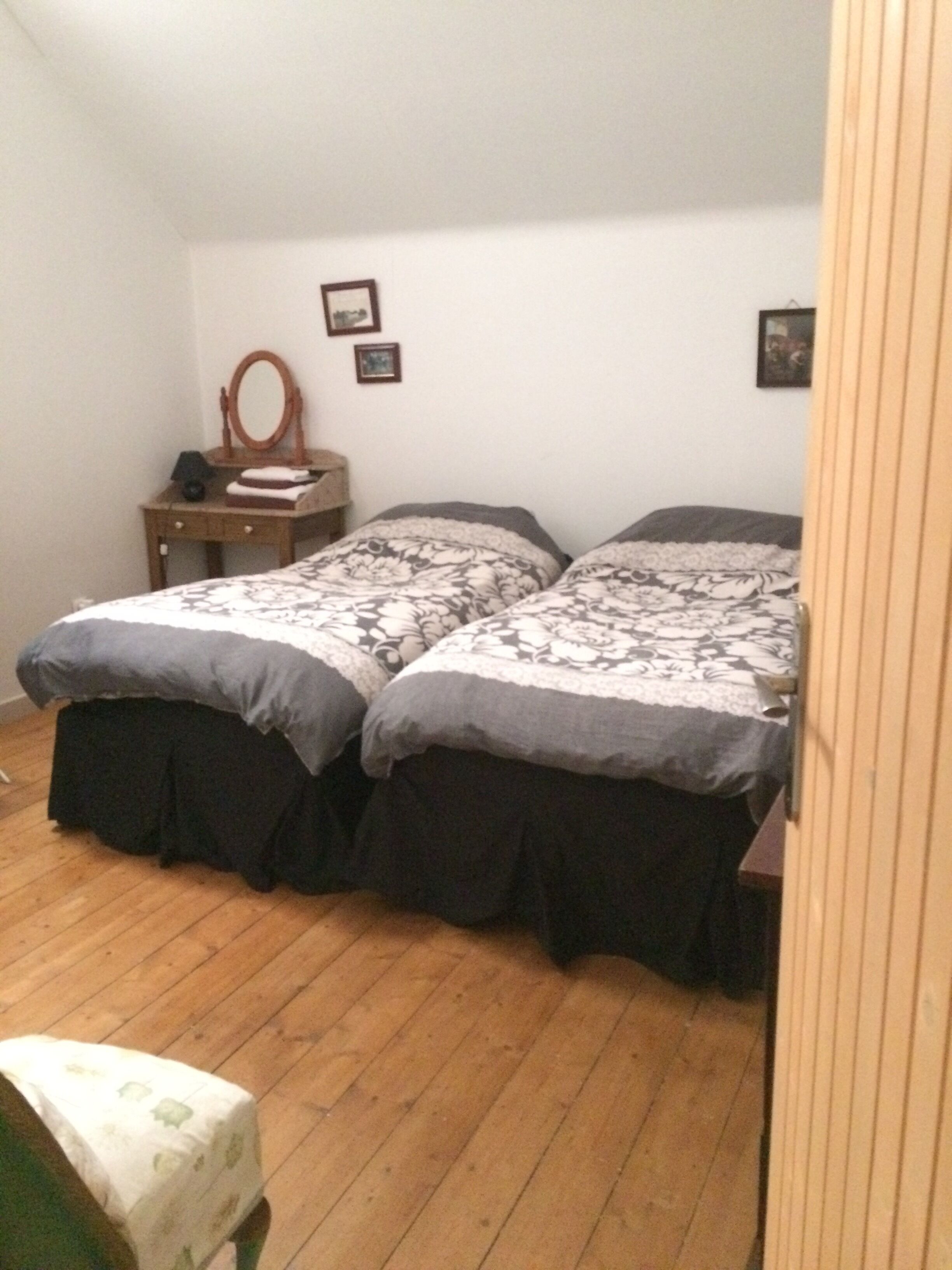 A bedroom with two beds, a wooden dresser, and a mirror.