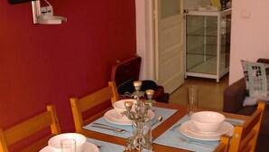 Una mesa de comedor dispuesta con platos, tazones y cubiertos, con un televisor montado en la pared superior.