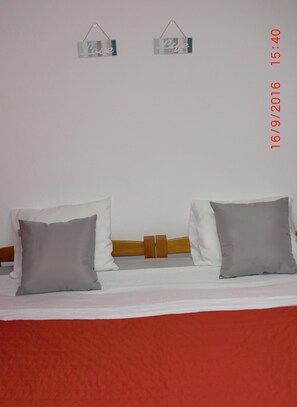A bed with two pillows, a wooden headboard, and two wall decorations. - The Yellow House :) (Vila Nova de Gaia)