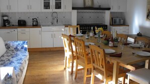 A kitchen with white cabinets, a wooden dining table, and chairs. There is a microwave, a kettle, and a sink. - Spacious family holiday gîte.... Country side, Brocéliande, Médiévale Josselin (La Grée-Saint-Laurent)