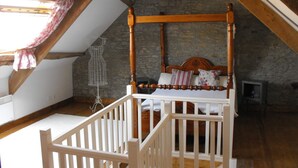 A bedroom with a four-poster bed, a white crib, and a stone wall. - Spacious family holiday gîte.... Country side, Brocéliande, Médiévale Josselin (La Grée-Saint-Laurent)