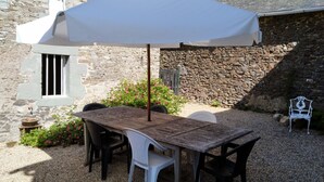 A stone building with a wooden table and chairs under a white umbrella. - Spacious family holiday gîte.... Country side, Brocéliande, Médiévale Josselin (La Grée-Saint-Laurent)