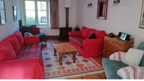A cozy living room with a red sofa, a blue sofa, a wooden coffee table, and a fireplace. - Spacious family holiday gîte.... Country side, Brocéliande, Médiévale Josselin (La Grée-Saint-Laurent)