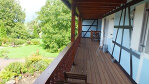 Een houten terras met uitzicht op een tuin en een gebouw met grote ramen.