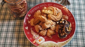 Een bord met gebakken snacks en een pot augurken op een geruit tafelkleed.