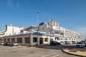 A row of white buildings with blue-tiled roofs, parked cars, and a clear blue sky. - Blue Fin, your unfogettable getaway in Tarifa! ☀️ (Tarifa)