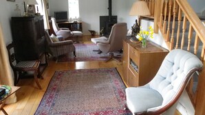 A spacious living room with a high ceiling, wooden flooring, a large rug, and a staircase leading to an upper level. - Pet friendly barn conversion with spectacular views, just for 2. (Crosby Garrett)