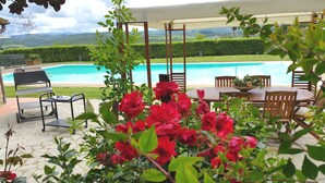 A poolside area with a covered seating area, a table, and chairs. - Stone house with private exclusive infinity pool in Chianti (San Filippo A Ponzano)