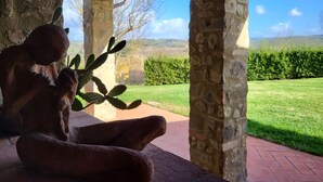 A stone structure with a cactus sculpture, a wooden ceiling, and a view of a green landscape. - Stone house with private exclusive infinity pool in Chianti (San Filippo A Ponzano)
