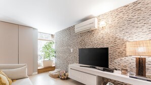 Een moderne woonkamer met een flatscreen-televisie, een witte console tafel en een wand met baksteenmotief.