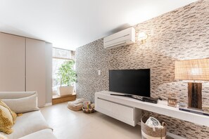 Uma sala de estar moderna com uma TV de tela plana, um console branco e uma parede com padrão de tijolos.