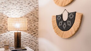 Een moderne kamer met een bakstenen muur, een houten vloerlamp en twee decoratieve wandobjecten.