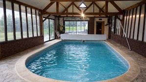 Ein Hallenbad mit Steinböden, Holzbalken und großen Fenstern.