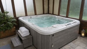 Ein Whirlpool mit Holzverkleidung, einer Bedienkonsole und einem Stapel Handtücher.