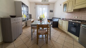Una cocina compacta con mesa, sillas, refrigerador, horno y pileta.