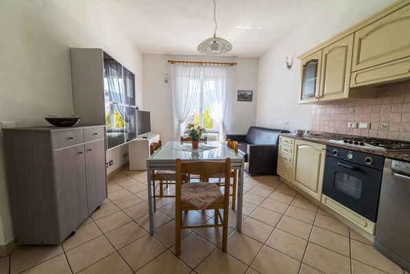 A compact kitchen with a dining table, chairs, a refrigerator, an oven, and a sink. - Close to the sea on the bike path (IMPERIA)