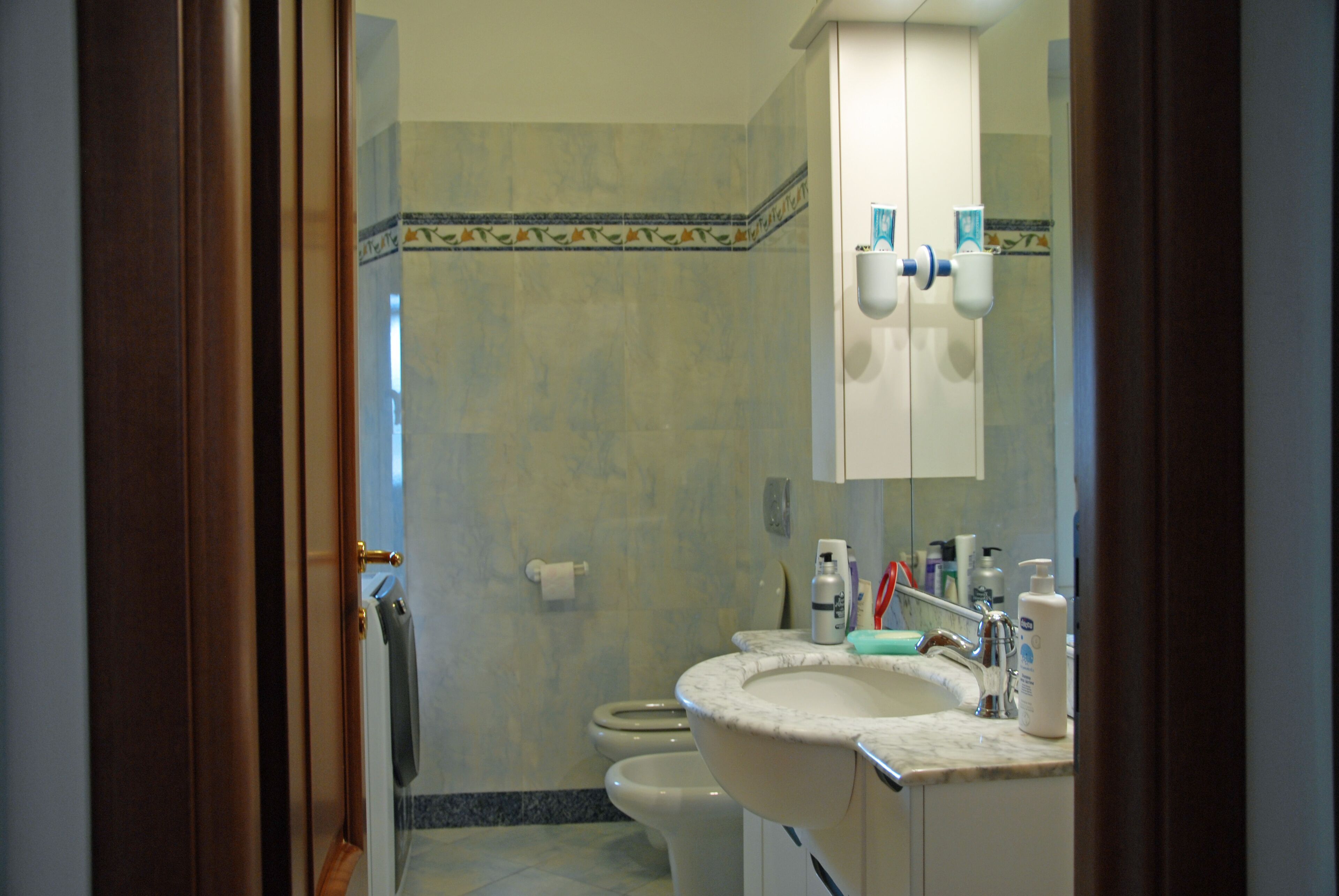 A bathroom with a sink, toilet, and mirror.