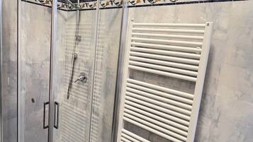 A glass-enclosed shower with a white radiator beside it.