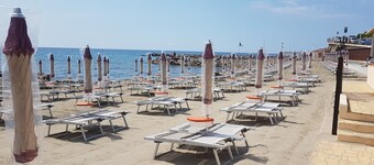 Près de la mer ensoleillée au centre avec deux chaises longues et un parasol sur le sable