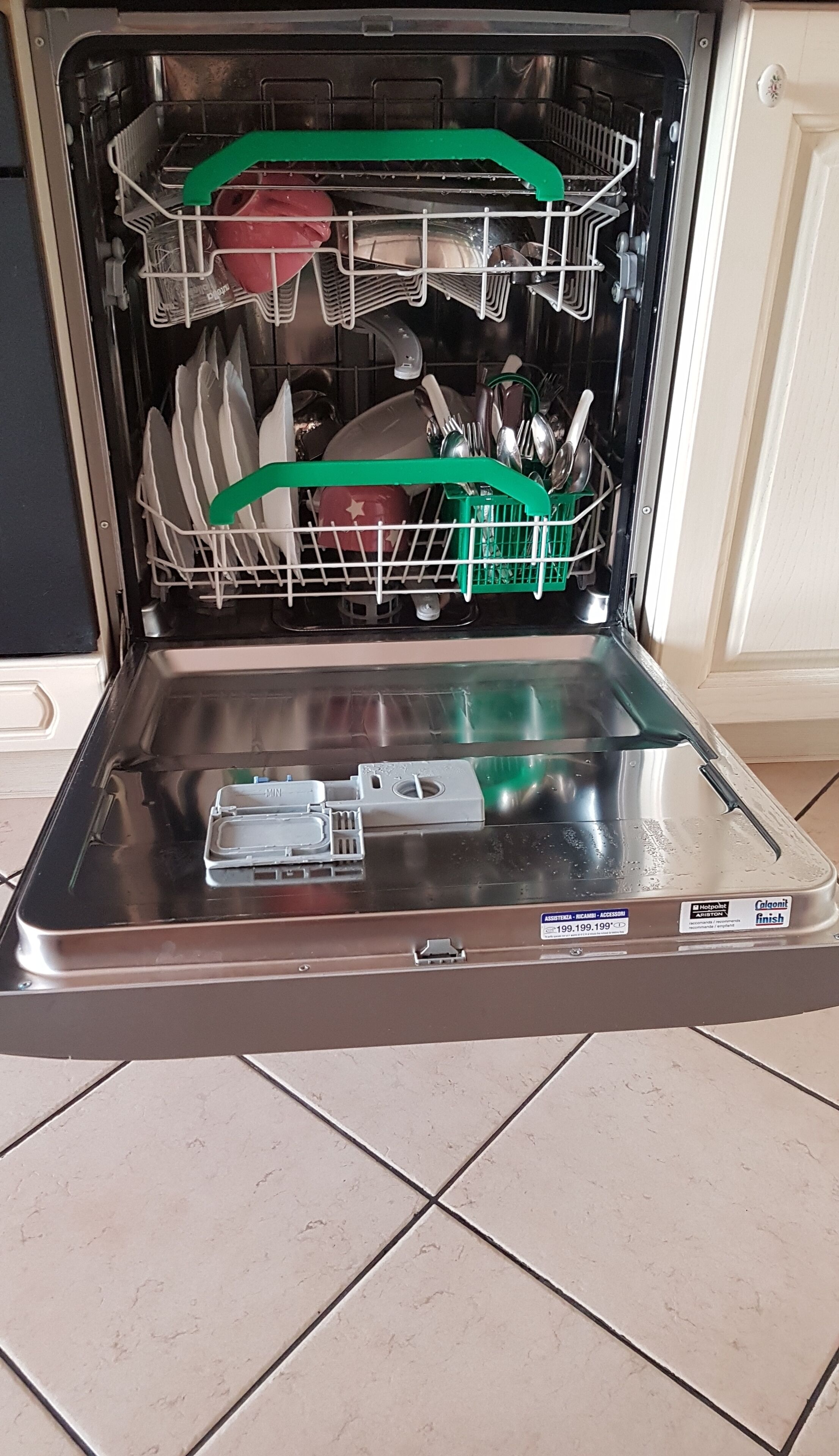 Un lave-vaisselle ouvert, avec ses étagères et ses ustensiles à l’intérieur.