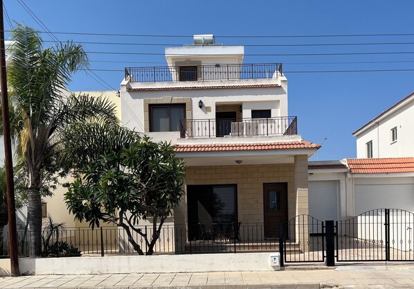 A two-story building with a balcony, a garage, and a gated entrance.