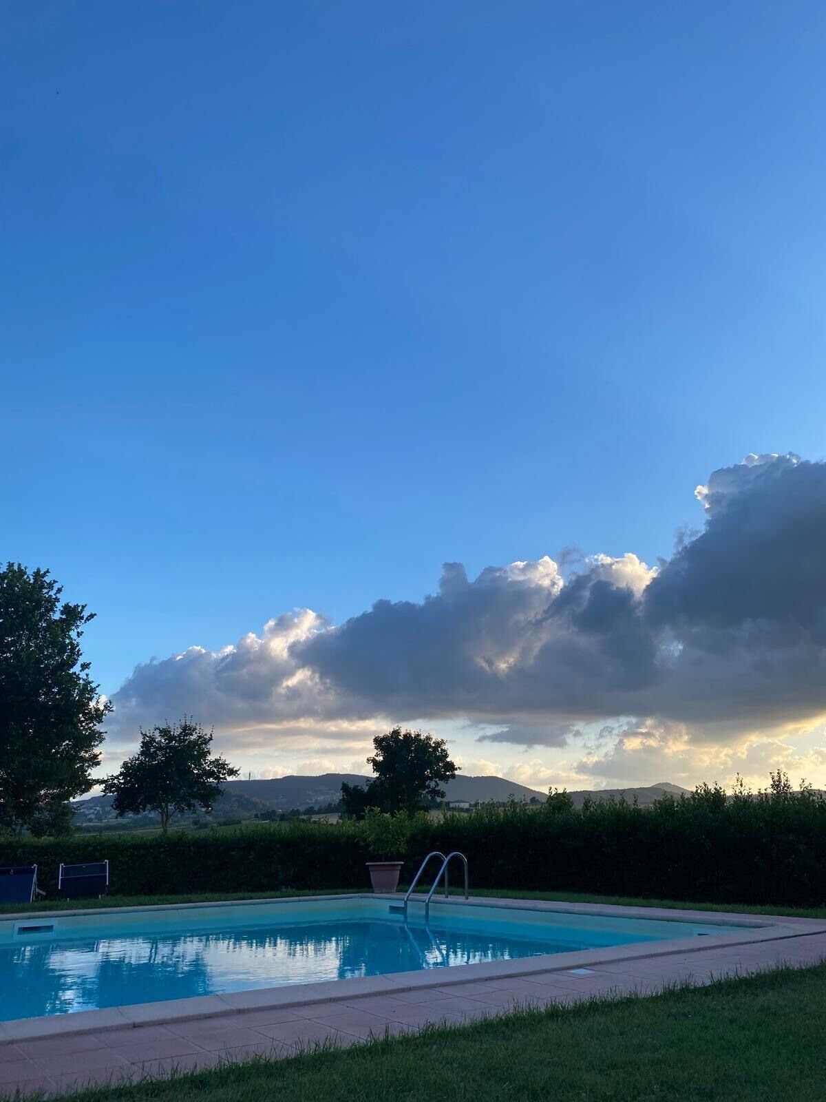 Una piscina amb un cel blau i muntanyes al fons.