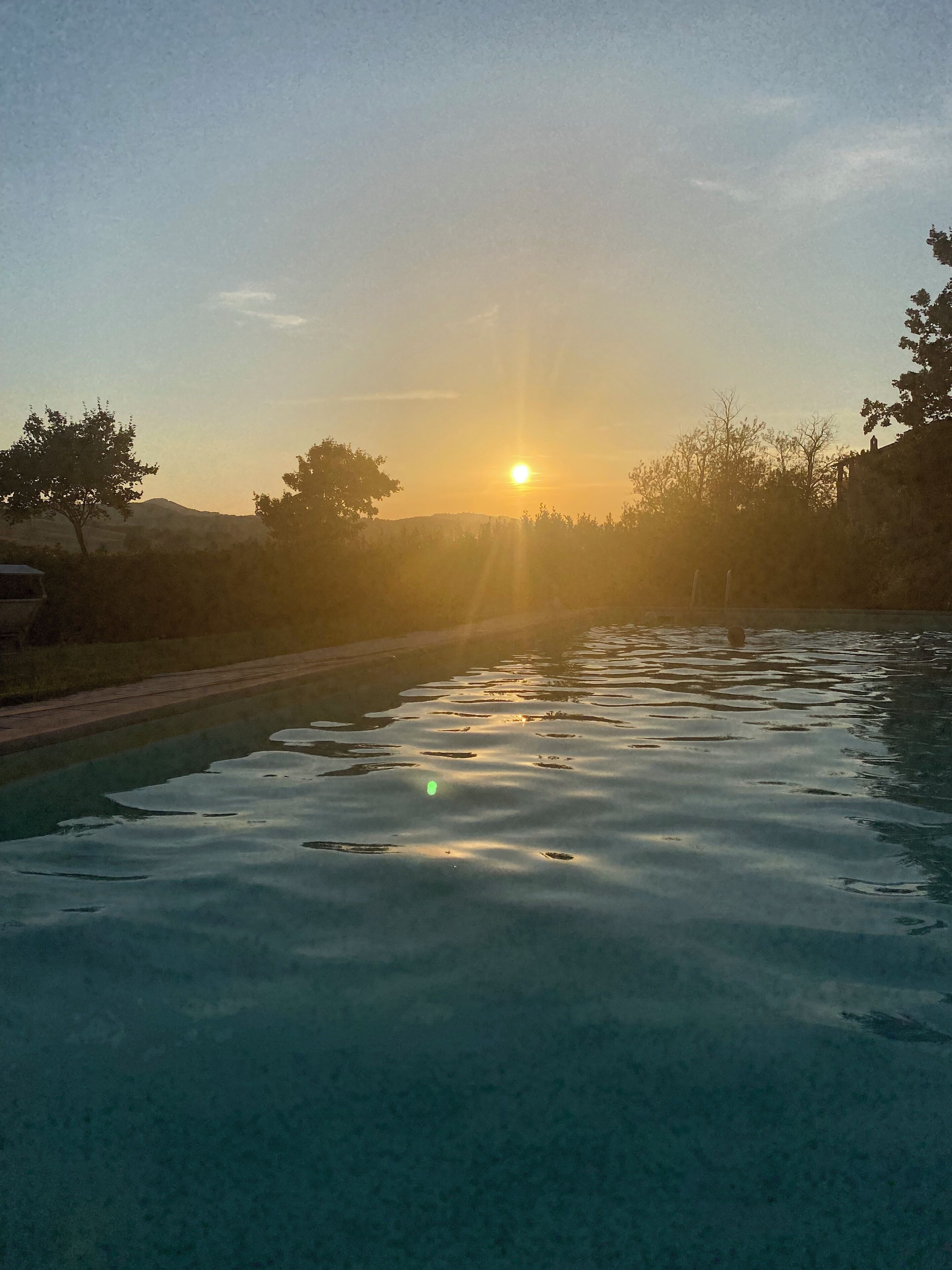 A swimming pool with a sunset in the background.