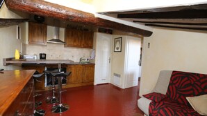 Una cocina con armarios de madera, una barra con taburetes y suelo rojo.