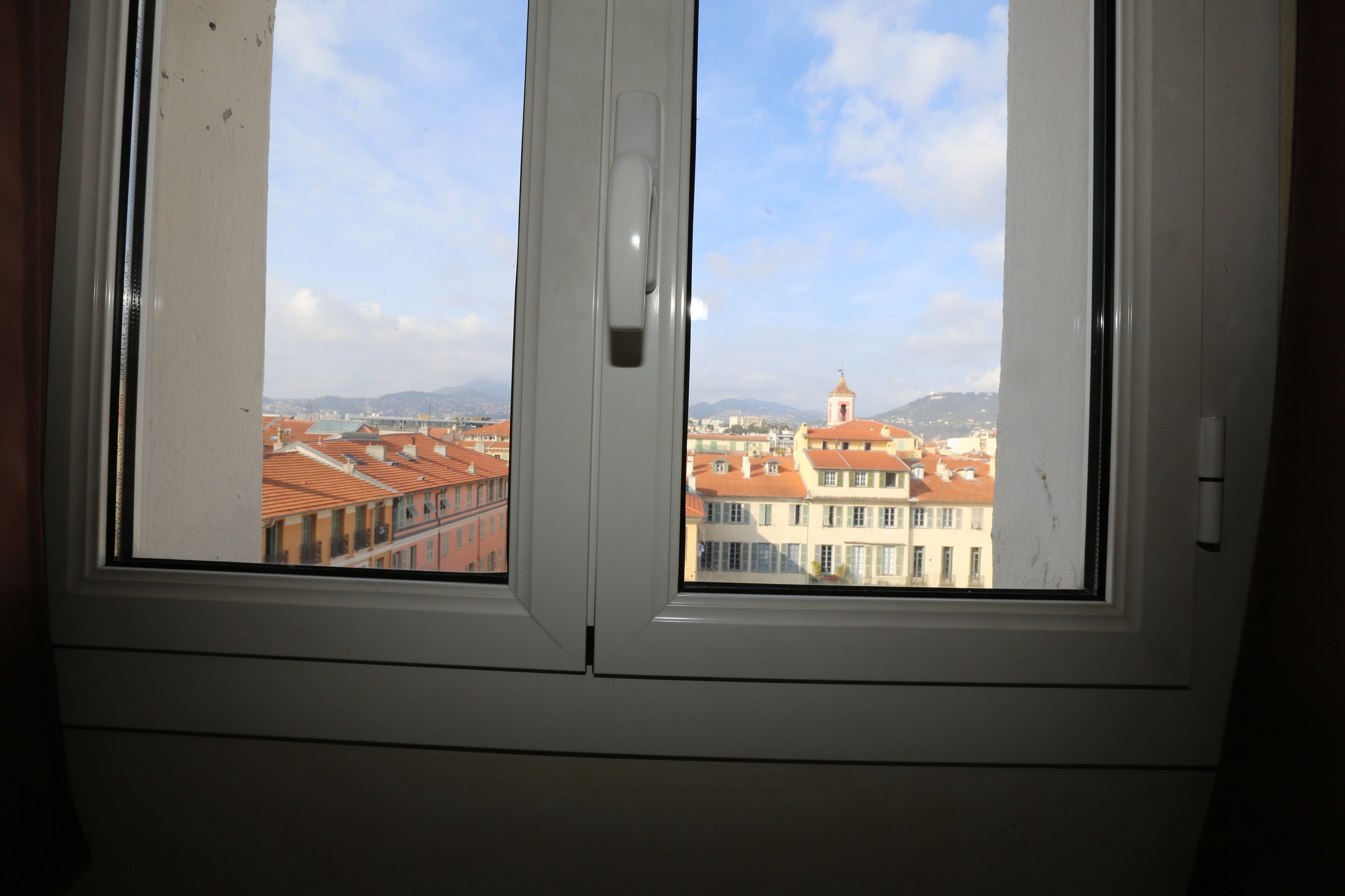 A window with a view of a cityscape, including buildings and a tower.