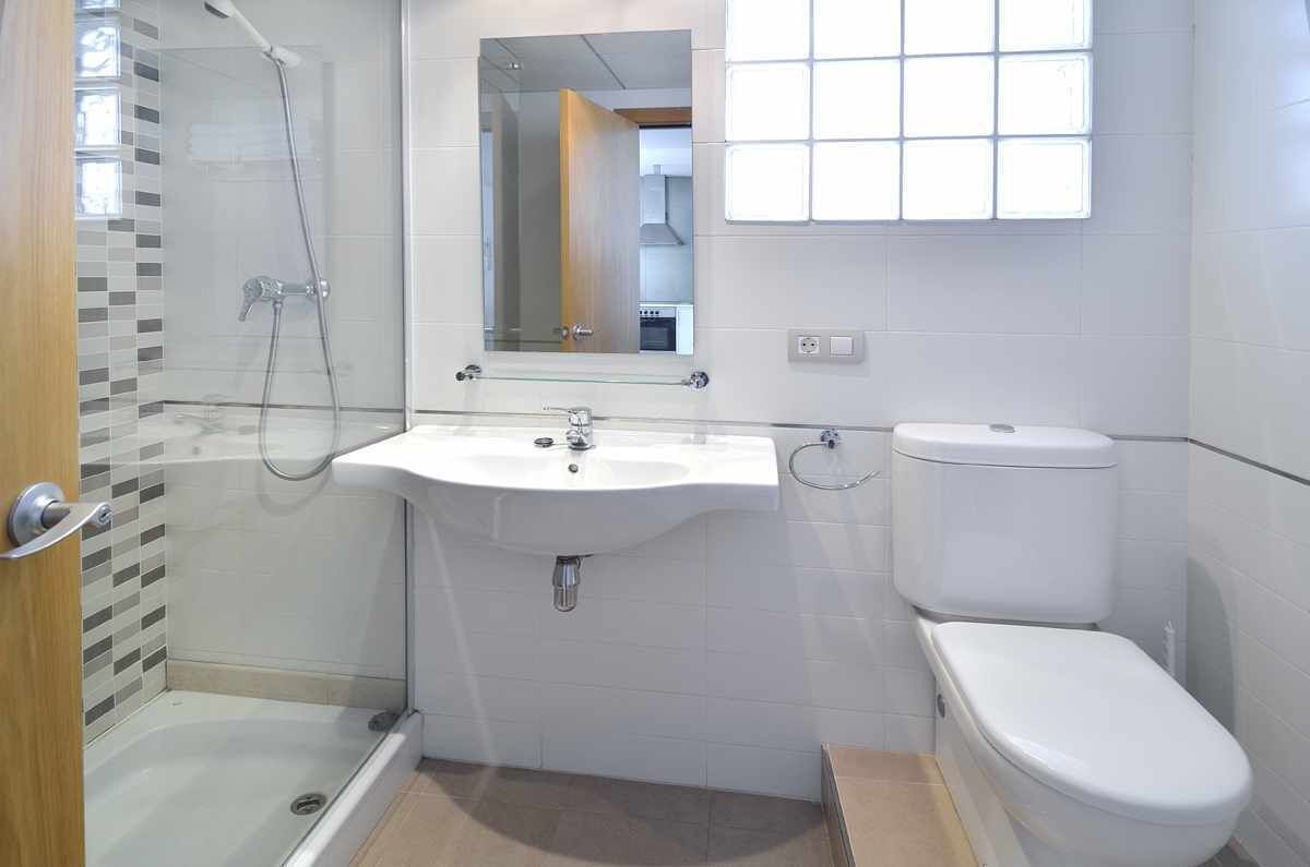 Une salle de bain avec une douche à parois de verre, un lavabo blanc et des toilettes.