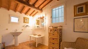 Casa de banho com lavatório, toucador, espelho e cestos de vime.