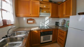 A kitchen with wooden cabinets, a stainless steel sink, a dishwasher, and a refrigerator.