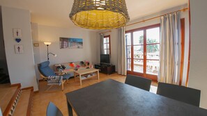 A living room with a sofa, a coffee table, a TV, and a dining table.